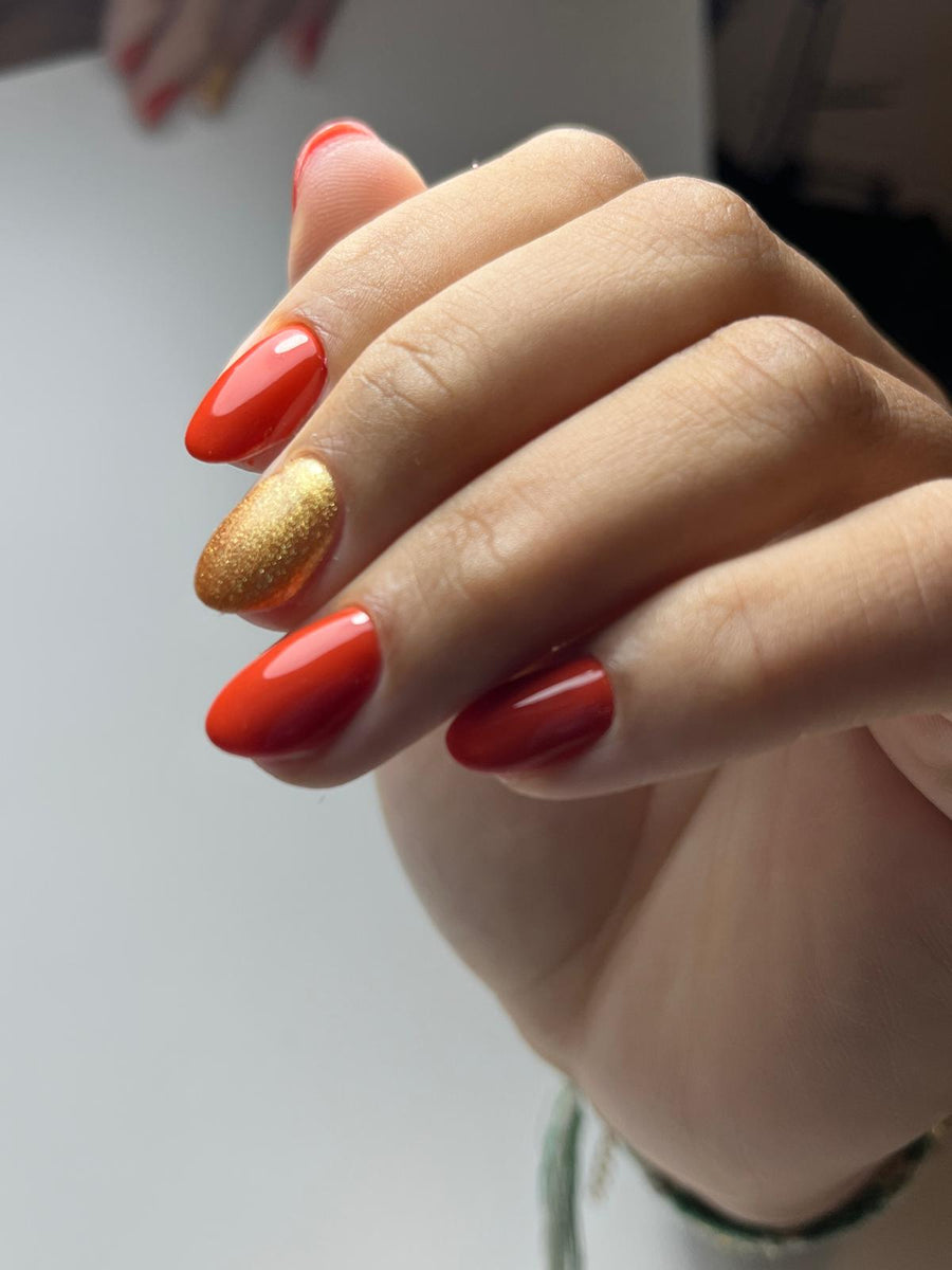 Manucure rouge brillant avec un accent nail doré pailleté